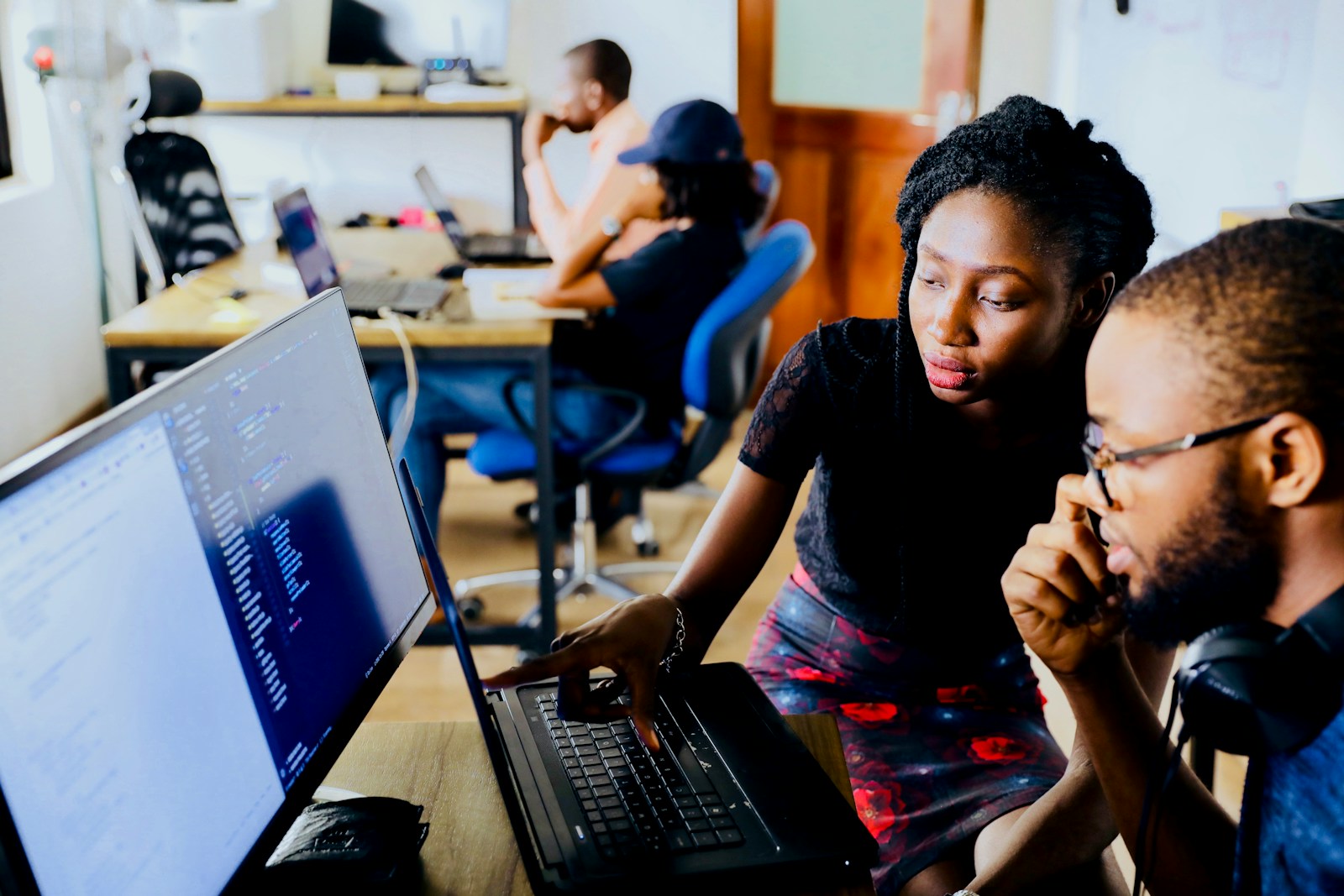 Young African innovators working together on a prototype at a laptop in a technology hub
